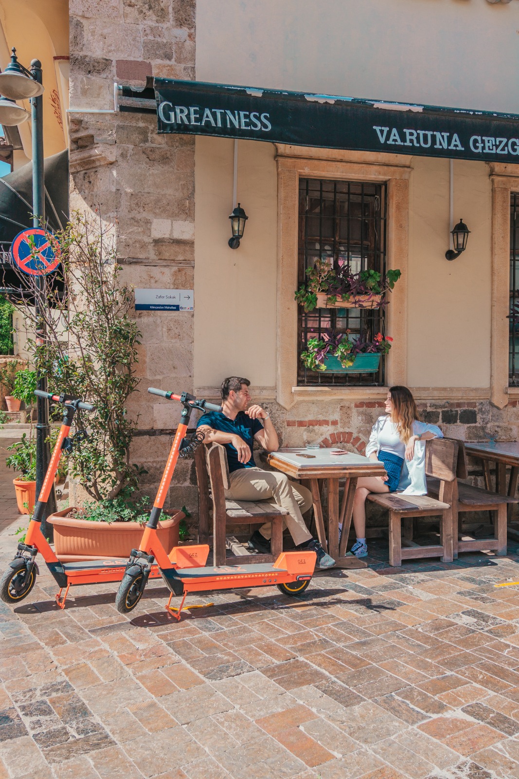 Kaleiçi’nde bir kafenin önünde park edilmiş turuncu GEZ scooterlar